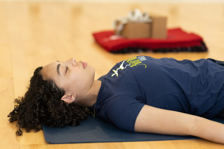 woman laying on her back on a yoga mat