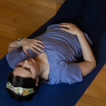 Woman lying on yoga mat in constructive rest pose practicing breath work